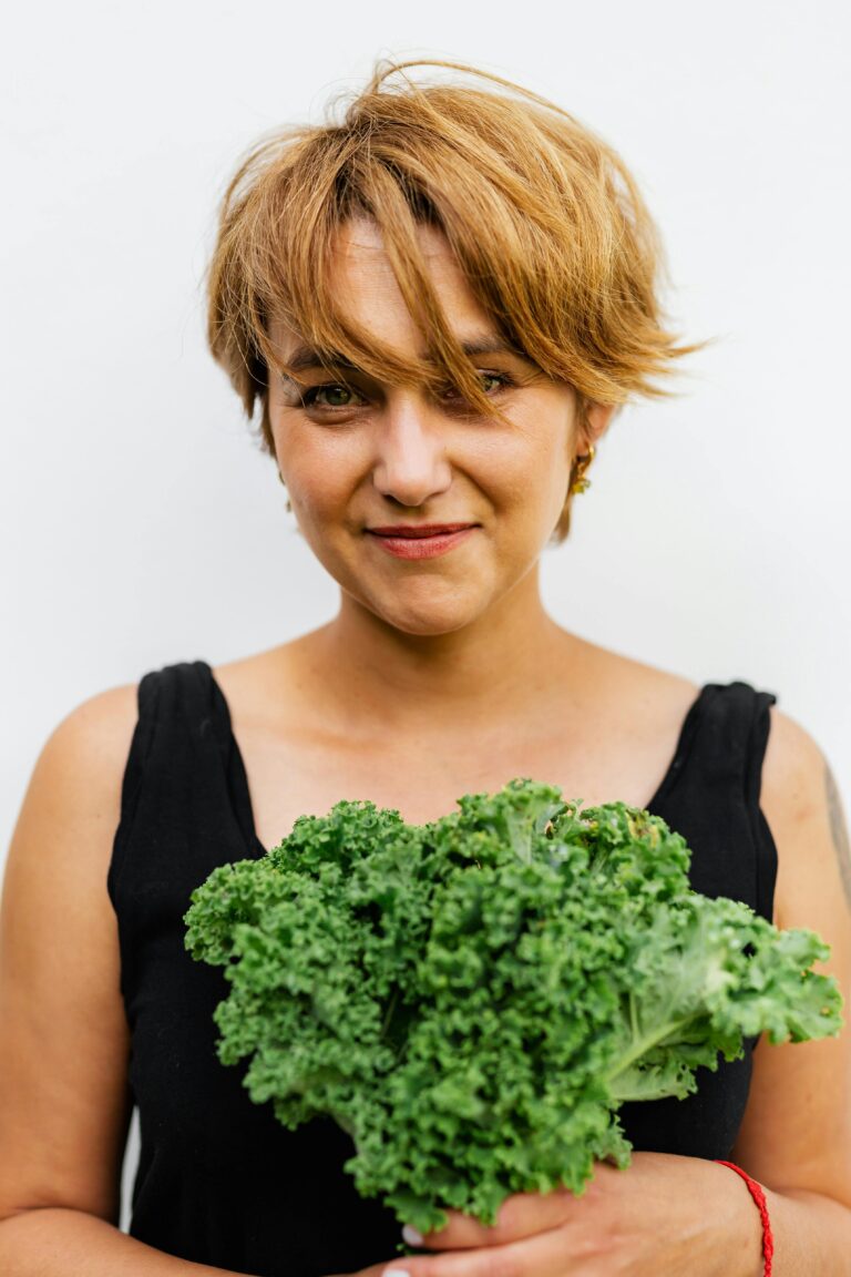 Portrait of a woman holding fresh kale against a white background, exuding a healthy lifestyle vibe.