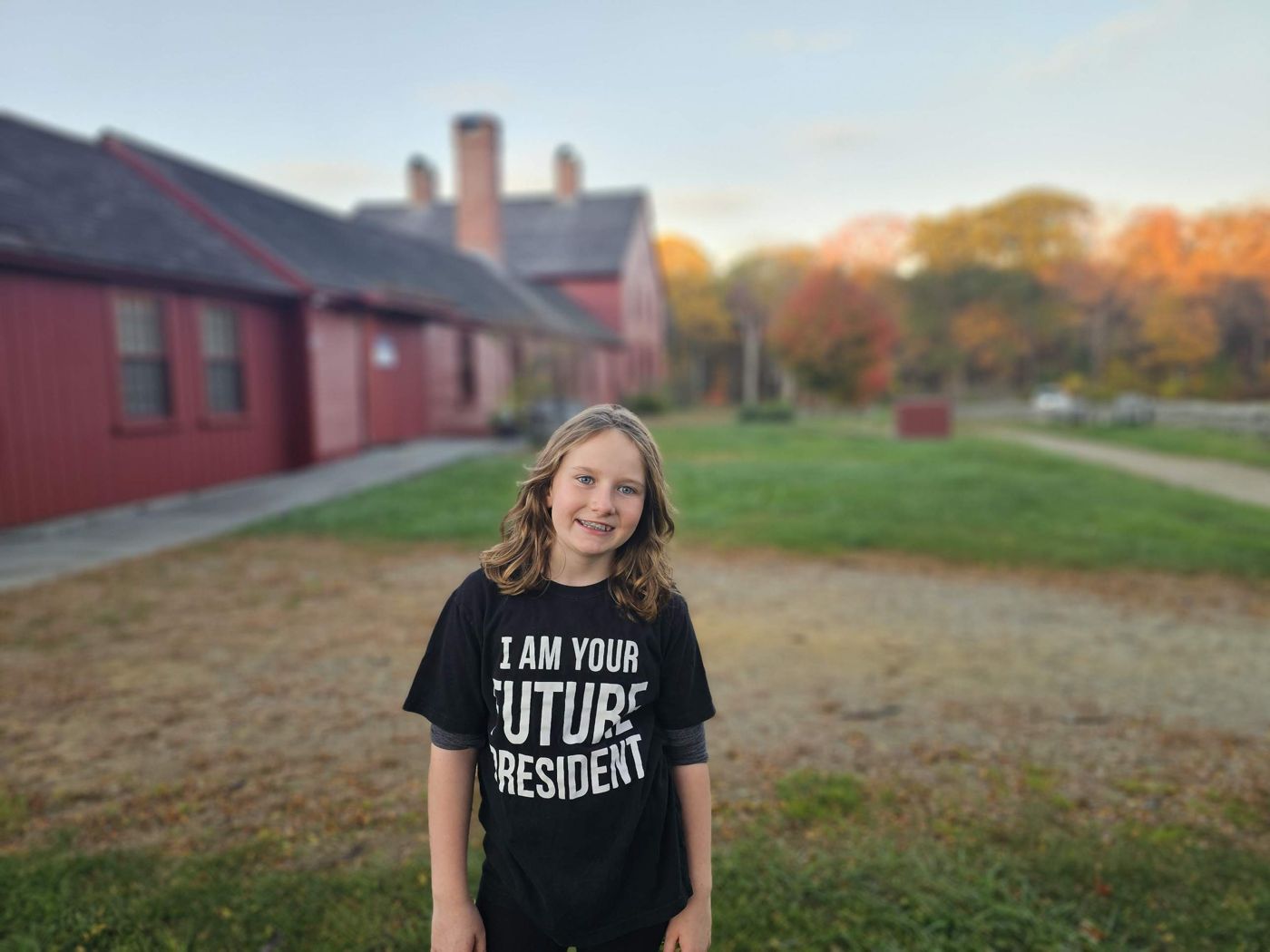 Adeline smiling on the lawn of a historic red farmhouse in Coventry