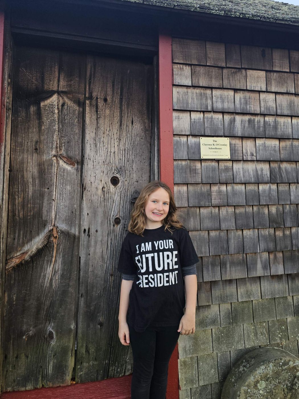Adeline in front of a historic one-room schoolhouse